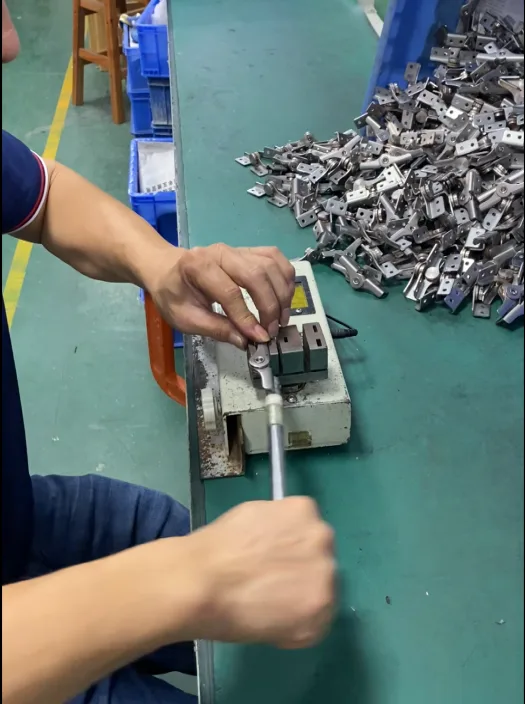 Worker performing a functional torque check on hinges using a production fixture